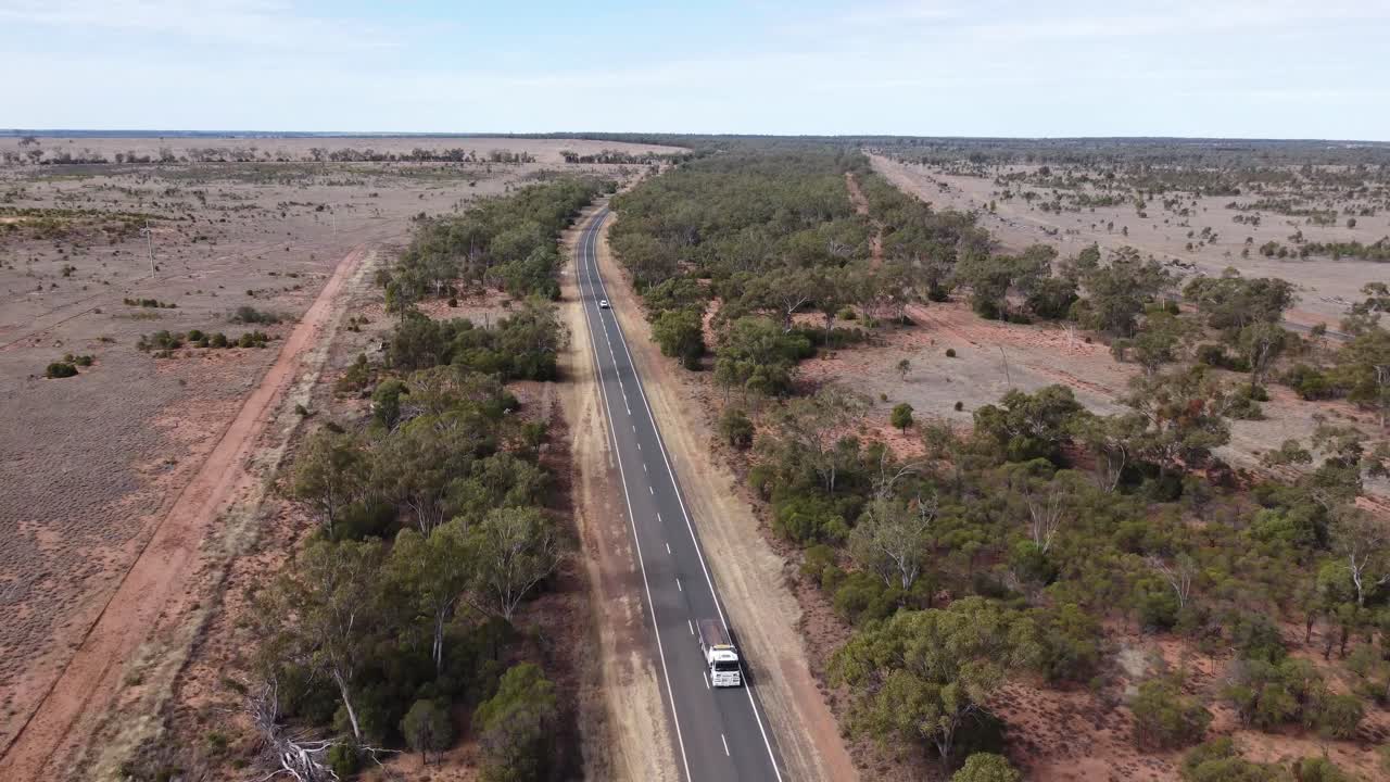 avión no tripulado volando backwoods sobre una carretera de campo, camión y coches que pasan por