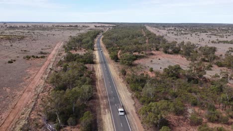 drone flying backwoods over a country road, truck and cars passing by