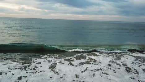 Drone-shot-with-the-sea-rising-towards-the-beach-with-the-wave-breaking-on-the-Mexican-coast-of-Los-Cabos