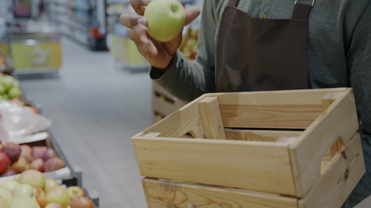 Person holding a green apple and a wooden crate full of apples