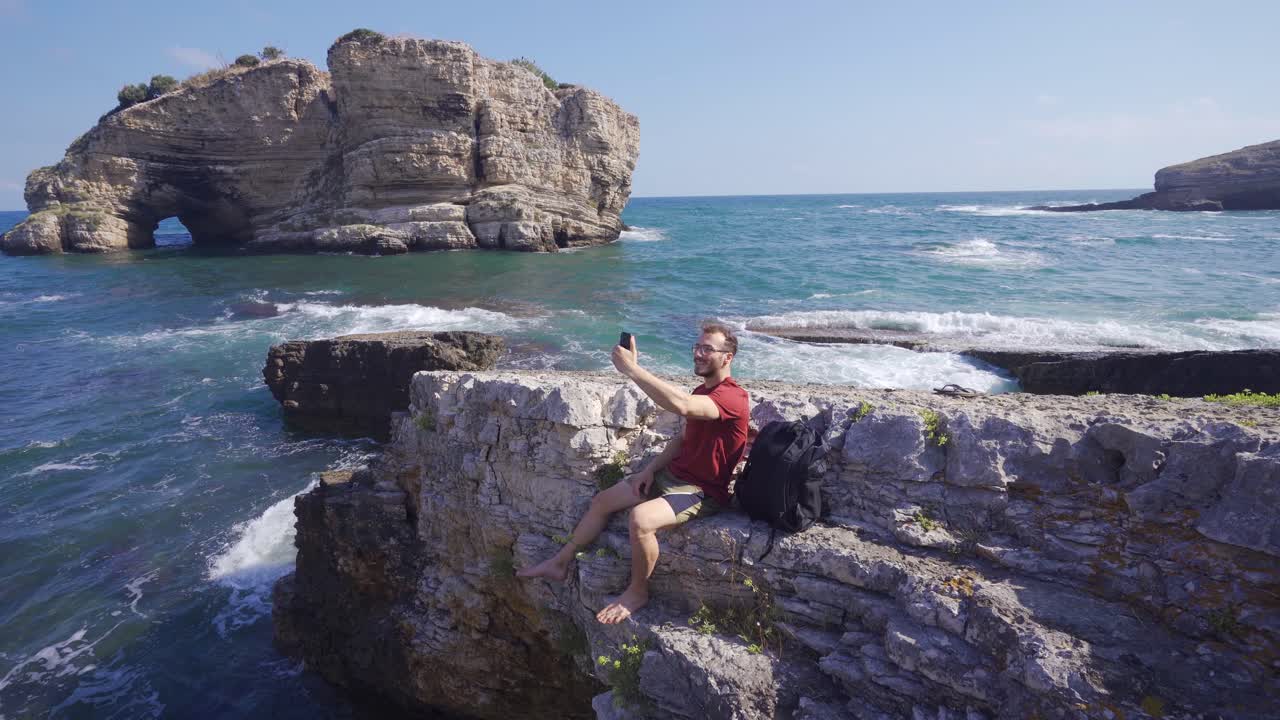 hombre sentado en la playa hablando por teléfono.