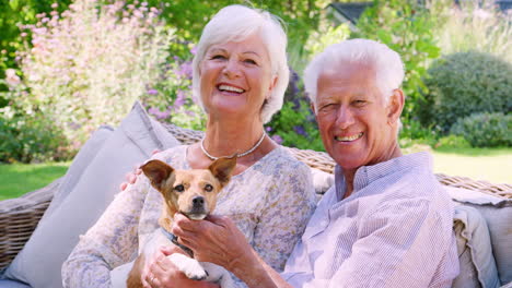 happy senior couple sitting with a pet dog in the garden