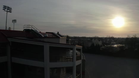 mccoy stadium in pawtucket rhode island, rising drone shot of back of abandoned stadium into the sun, aerial