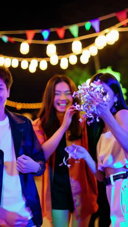 young adults celebrating and dancing with confetti at a night party