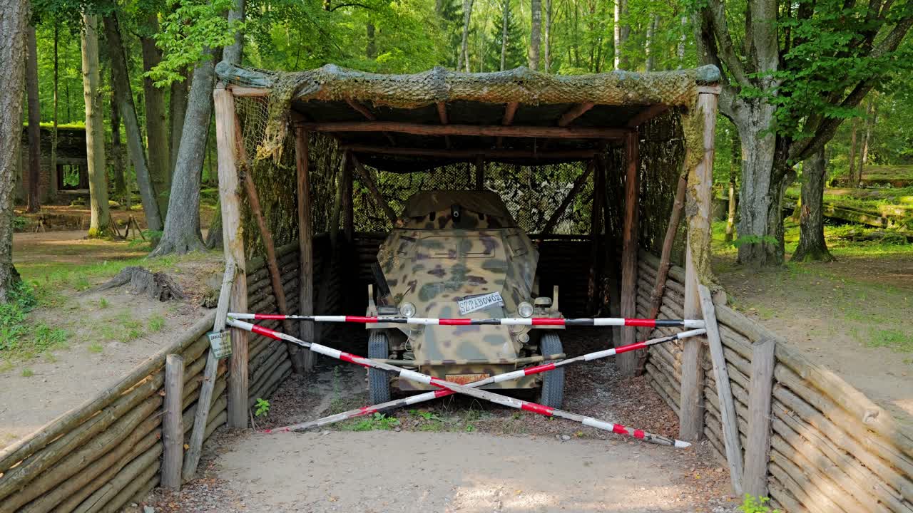 Camouflaged German half-track vehicle stands preserved in forest war shelter