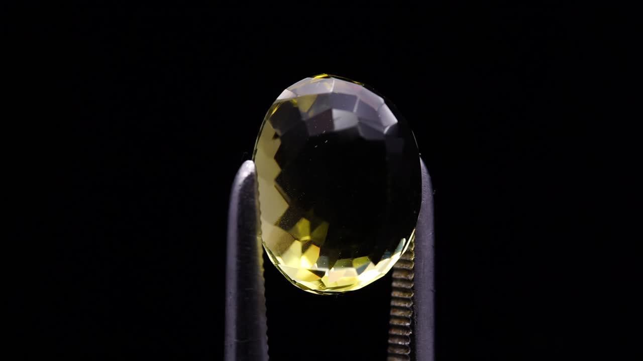 자연 황색 시트린은 회전 테이블에 있는 핀세저에 있습니다.