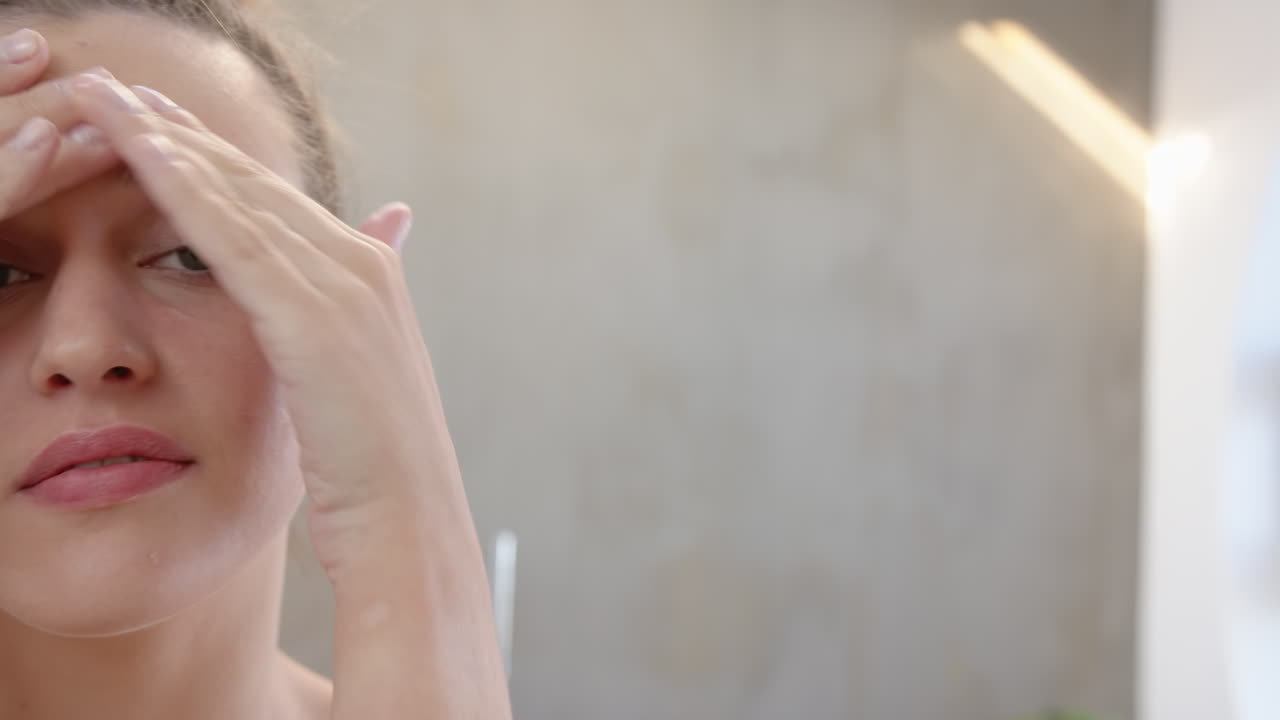 Applying facial cream, young woman focusing on skincare routine in bathroom, copy space