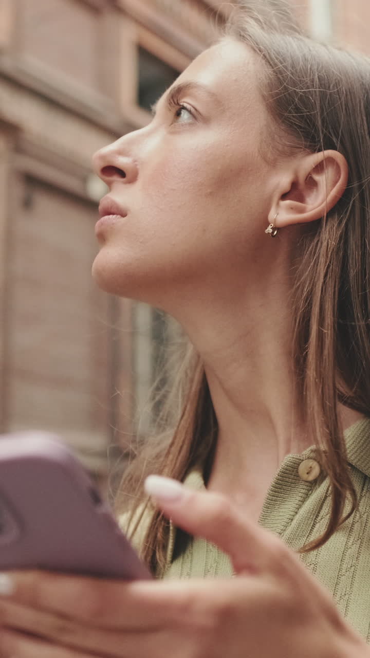 Giovane donna che usa lo smartphone all'aperto e si guarda intorno