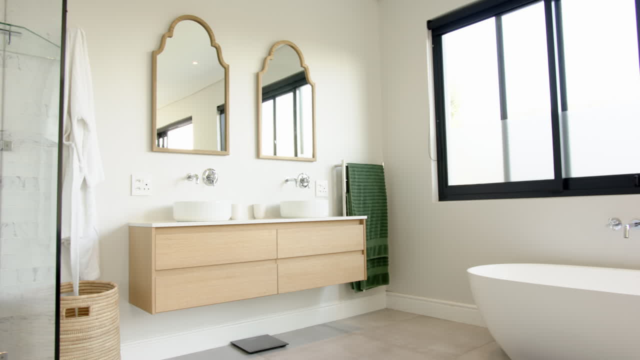 Modern bathroom featuring double sinks, mirrors, and freestanding bathtub, copy space