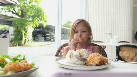 little girl eating chicken and rice in a cafe