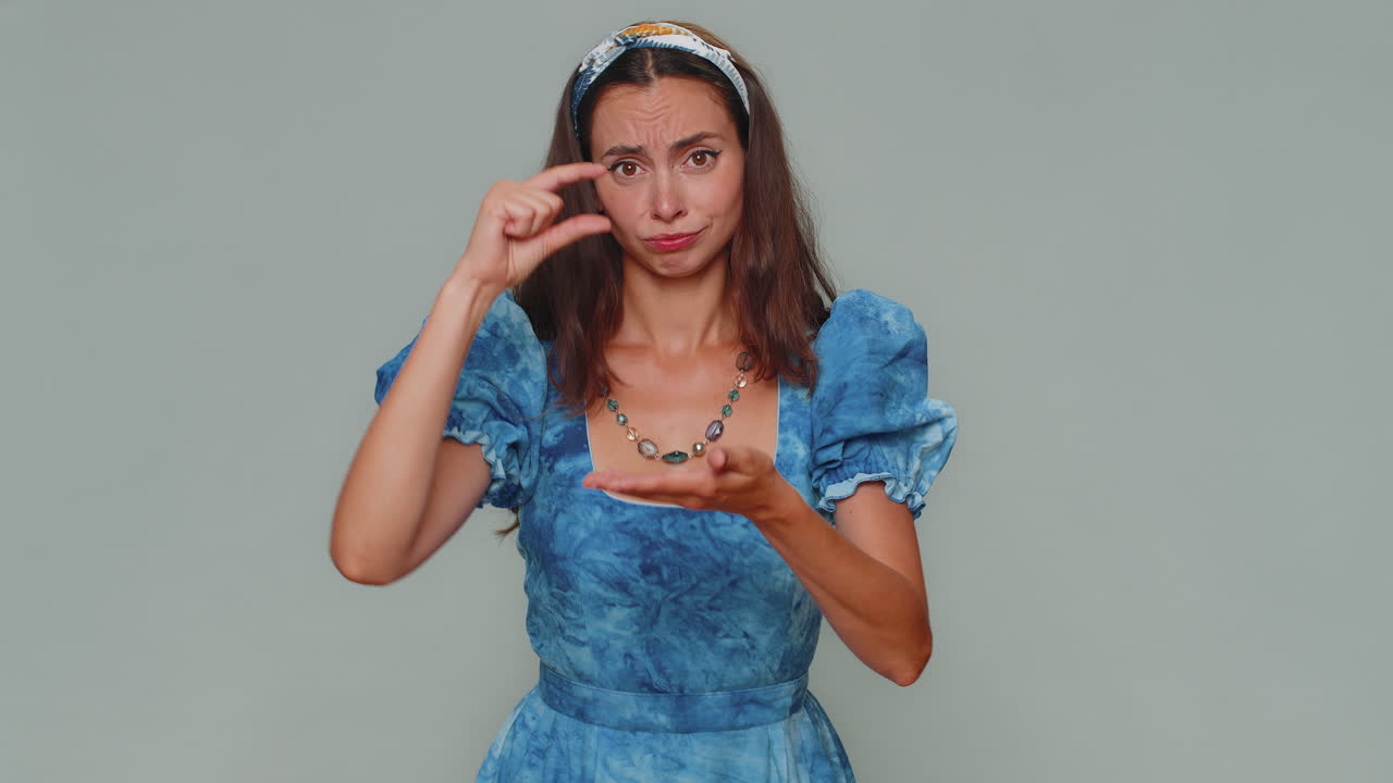 여성은 회의적인 미소와 함께 약간의 제스처를 보여주고, 최소한의 표시를 보여주고, 작은 크기를 측정합니다.