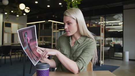 caucasian businesswoman having a video chat going through paperwork in modern office