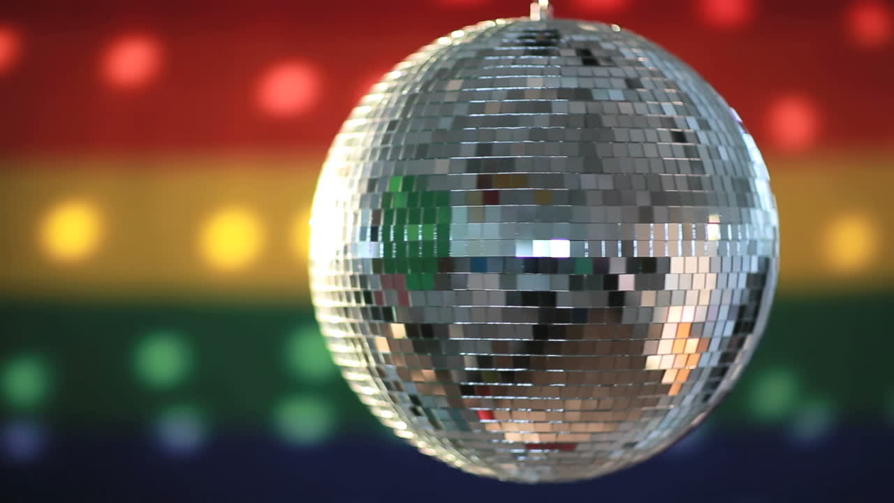 bola de discoteca girando contra la bandera del orgullo gay