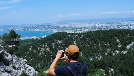 man taking a panorama on top of marseilleveyre with view of marseille, pan right, in the calanques