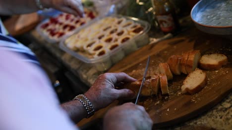 Toma-Por-Encima-Del-Hombro-De-Una-Mujer-Cortando-Una-Pequeña-Hogaza-De-Pan-En-Rebanadas-Pequeñas