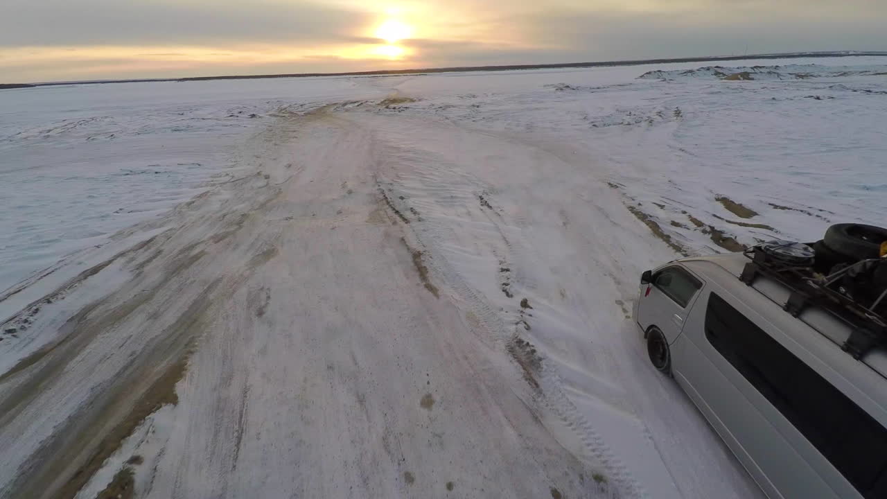 트럭이 시베리아의 러시아 북극에서 얼어붙은 툰드라를 가로질러 운전할 때의 공중