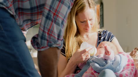 Mid-adult-caucasian-parents-feeding-milk-her-baby-from-bottle-in-a-comfortable-home-4k