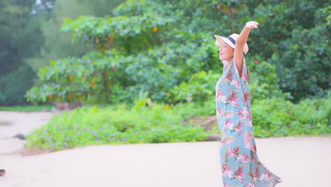 A-pretty-young-woman-in-a-print-coverup-walks-along-the-beach-twirls-with-joy