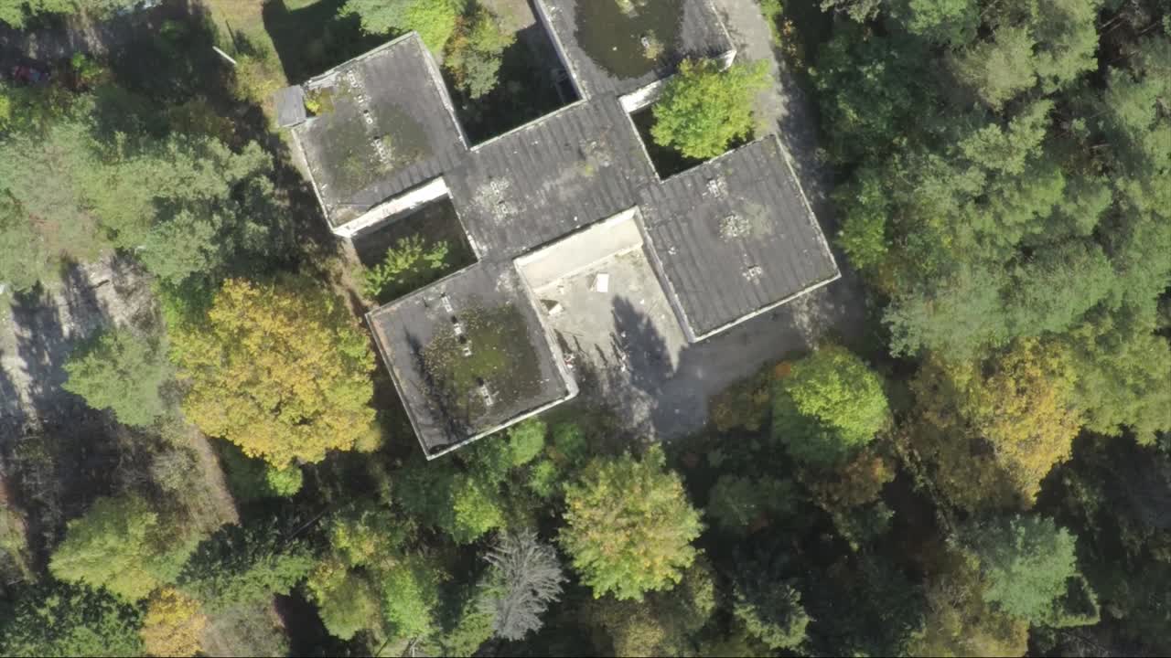 vista aérea de un edificio abandonado rodeado de bosque en otoño