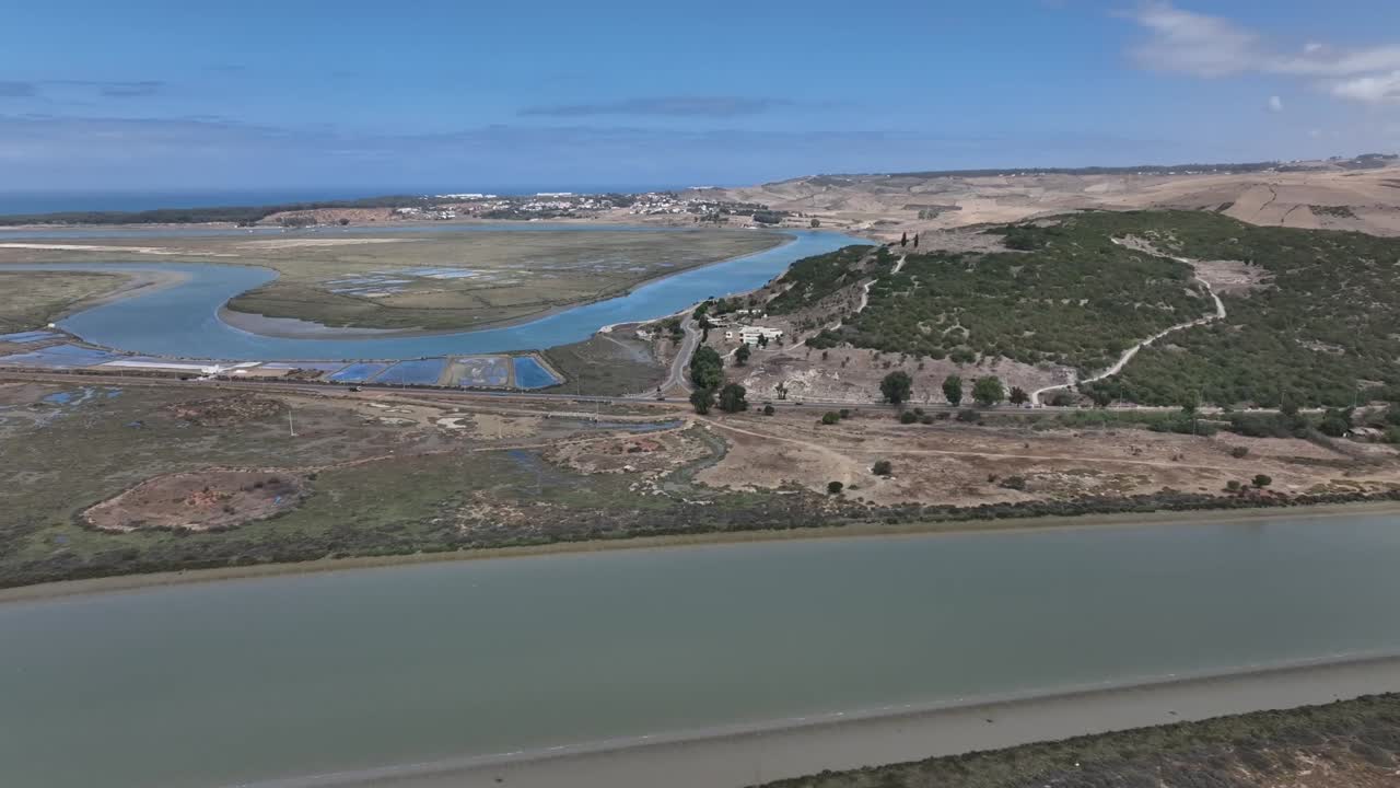 Cinematic drone shot capturing the mythical Lixus site and the twisting Loukkos River resembling a dragon, highlighting Morocco’s rich archaeological and legendary landscape