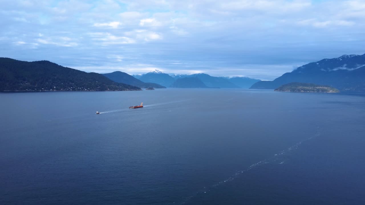 Aerial View of Cargo Ship and Tugboat Sailing Through a Fjord