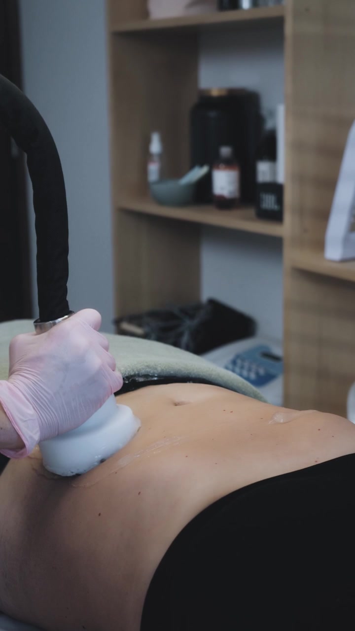 Professionista che esegue un trattamento di cavitazione ultrasonica sull'addome del cliente.