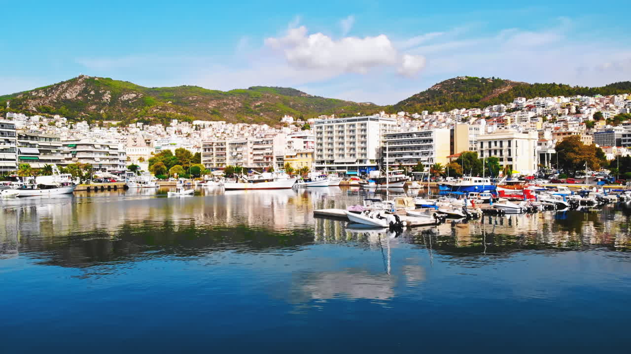 KAVALA, GREECE - SEPTEMBER 23, 2020: Aerial view of sea port, moored yachts and boats, cars on the road, green hills