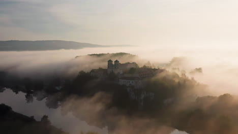 aerial drone view of benedictine abbey over vistula river in tyniec in the morning fog, krakow, poland