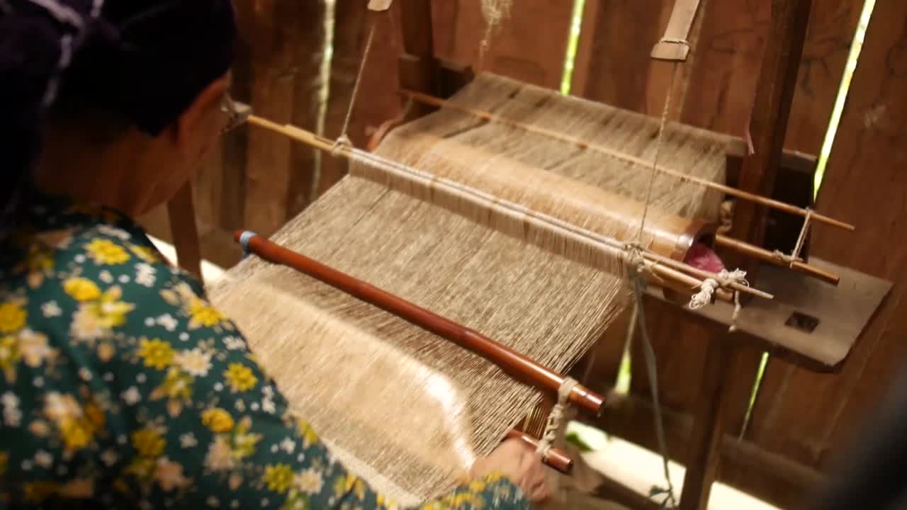 elder Vietnamese lady working on hennep tribal weave, cutting a rope, home workshop