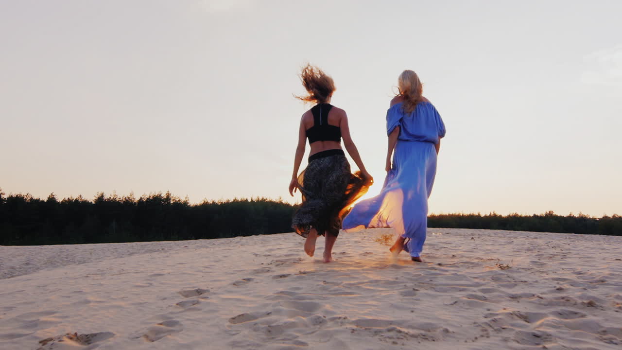 dos mujeres jóvenes con vestidos ligeros y aireados corren hacia el sol concepto libertad sueños de mujeres salud