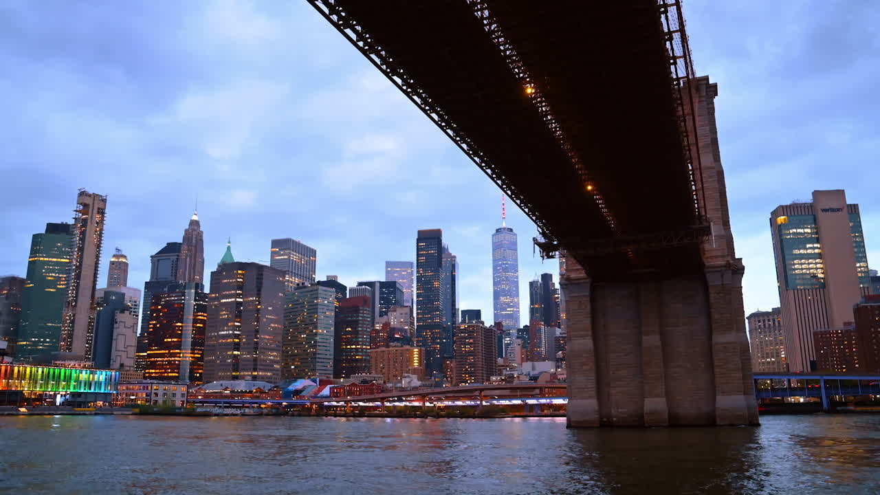 Travelling by the East River under the Brooklyn Bridge. Beautiful skyline of New York at backdrop
