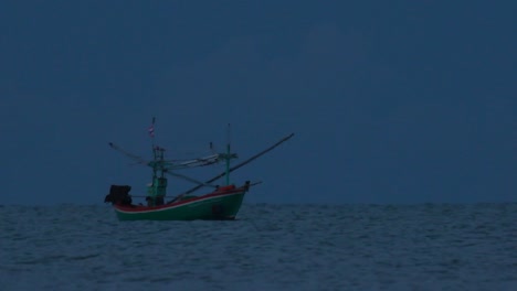 fishing boats in thailand wait in the middle of the ocean for dark to come so they can turn on their green lights and start fishing and troll for shrimps