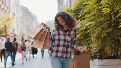 mujer joven feliz chica adicta a las compras consumidor después de la venta de compras con bolsas llenas caminando por la calle de la ciudad