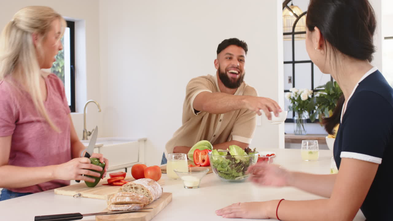 Preparing meal, young friends chopping vegetables and talking in kitchen