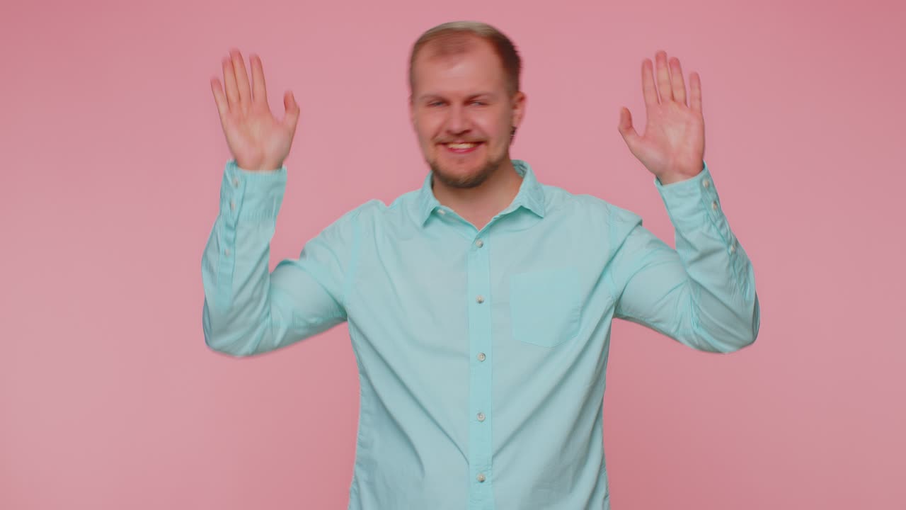 Bearded man smiling friendly at camera and waving hands gesturing hello or goodbye welcoming