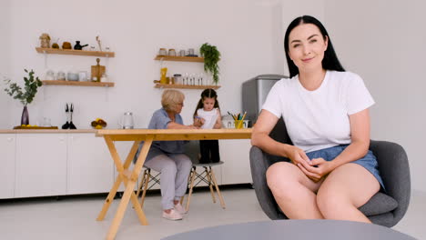 Mujer-Feliz-Y-Hermosa-Sentada-En-Una-Silla-Mirando-La-Cámara-Mientras-Hace-Una-Videollamada-En-Casa