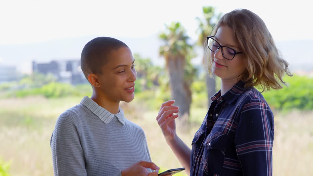 jóvenes ejecutivas caucásicas tomando selfies con teléfonos móviles en el balcón de la oficina 4k