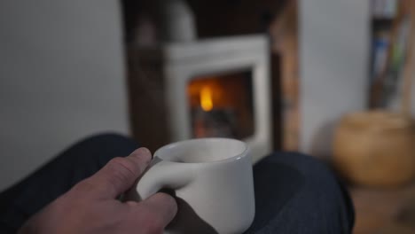 coffee mug in hand with lit stove in background