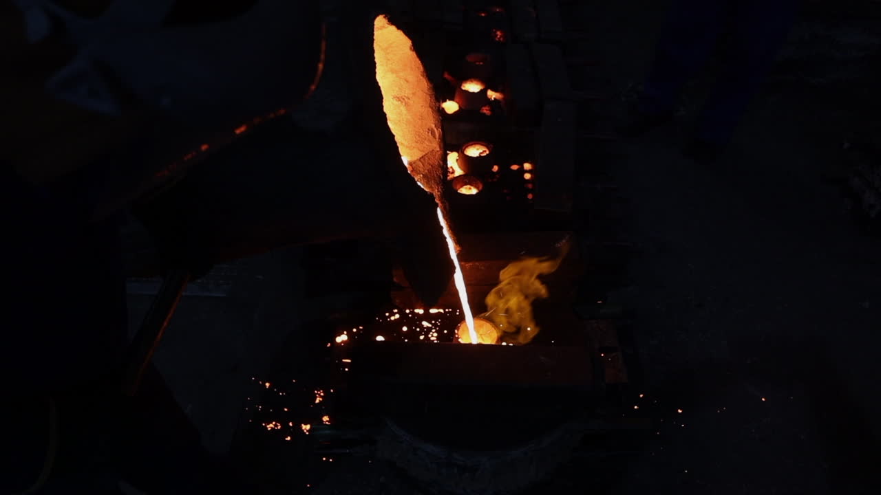 Bright orange molten alloy poured into manufacturing mold in foundry