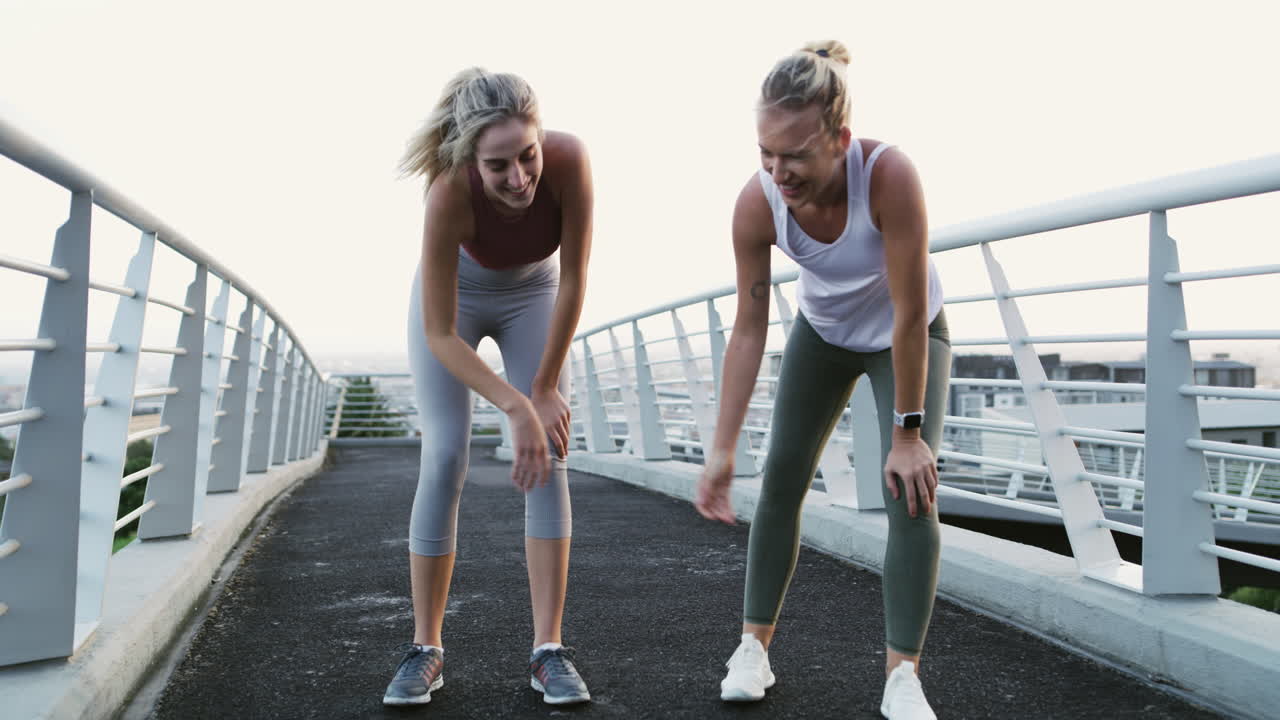 Two women resting after jogging/running on a bridge