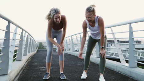 two women resting after jogging/running on a bridge