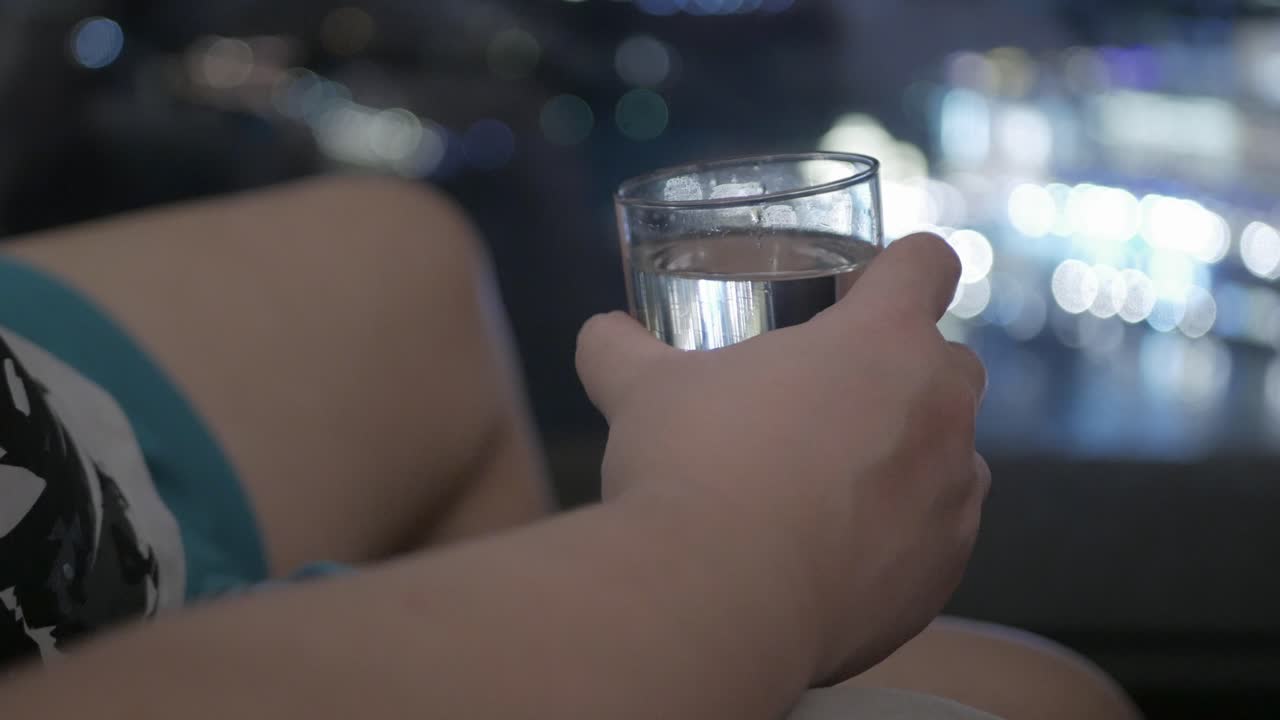 vista para tomar a mano un vaso de agua para beber mientras se relaja en el sofá en la sala de estar del hotel por la noche