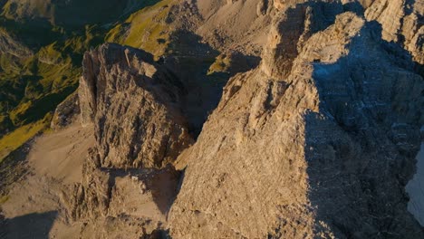 aerial tilt up shot of beautiful mountain range lighting by sunset light with green valley in italian dolomites