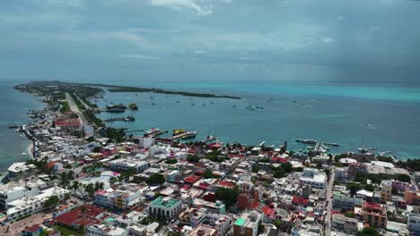 Vista-Aérea-Sobre-El-Paisaje-Urbano,-El-Puerto-Y-Los-Barcos-De-La-Soleada-Isla-Mujeres,-México