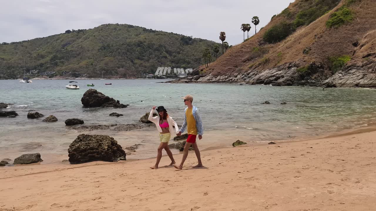 Una pareja caminando por una playa tropical.