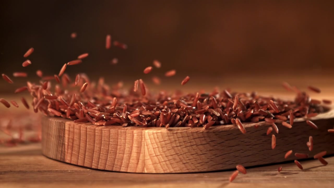 Red Rice Grains Falling onto a Wooden Board in Slow Motion