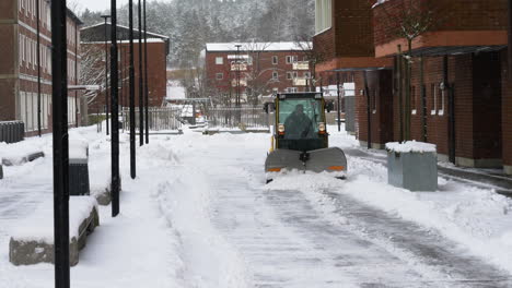 Small-cleaning-plow-removing-snow-from-street,-Gimbal-shot,-Soft-Snow-Falling