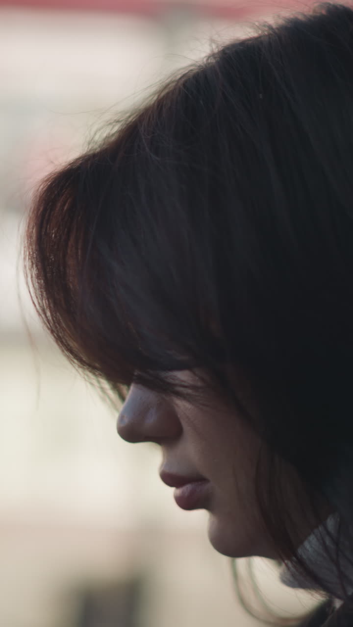 Profile view of thoughtful woman with soft lighting and blurred urban background, showcasing natural beauty and introspection in an outdoor setting