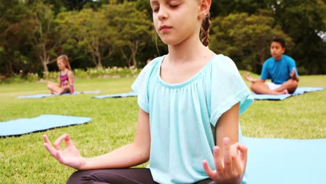 group of kids performing yoga in park