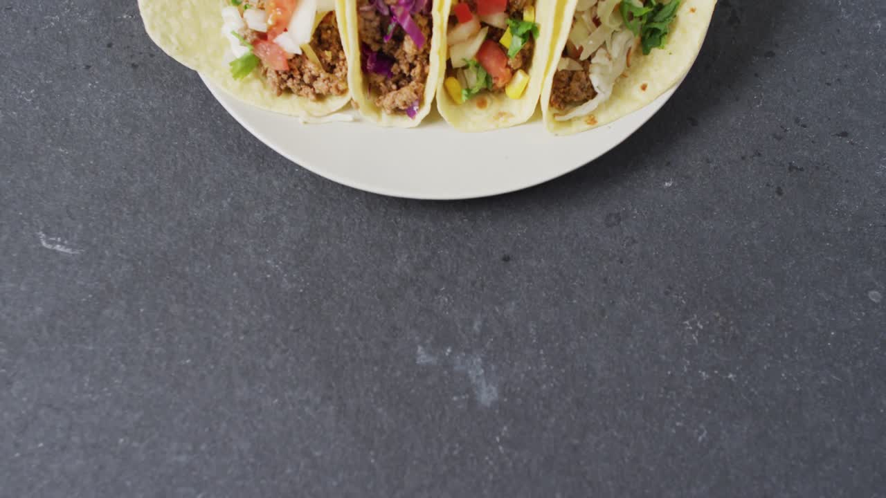 video de tacos recién preparados en un plato sobre un fondo gris